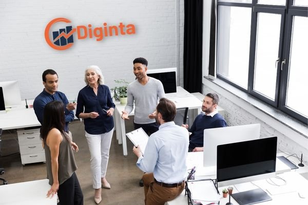 Image showcasing the Diginta Marketing team in the office, with the old logo displayed on a wall behind